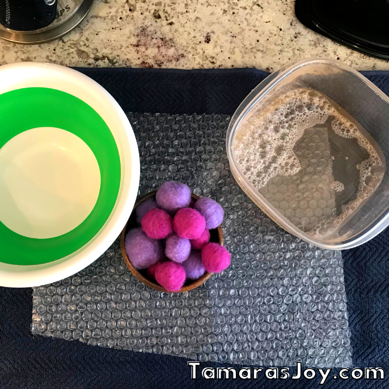 Showing a bowl and dry felted balls next to hot soapy water