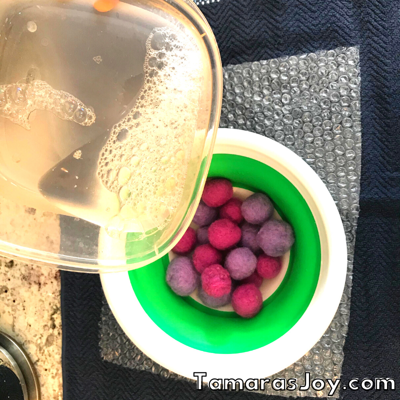 Pouring hot soapy water onto dry felted balls