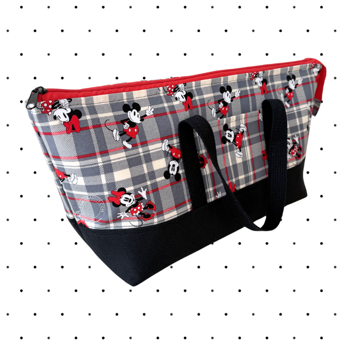 A fabric tote bag featuring a gray, red, and beige plaid pattern with repeating Mickey Mouse and Minnie Mouse motifs, finished with a solid black base and black webbed handles.