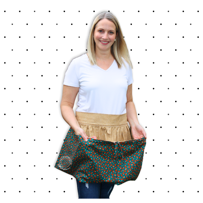 Woman wearing a patterned apron over a white shirt against a polka dot background