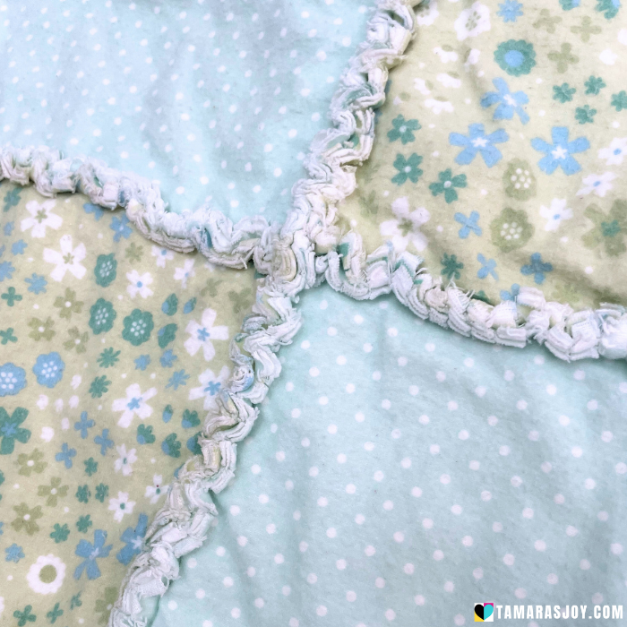 Two fabric patches with floral patterns and white rick rack trim on a light blue polka dot background.